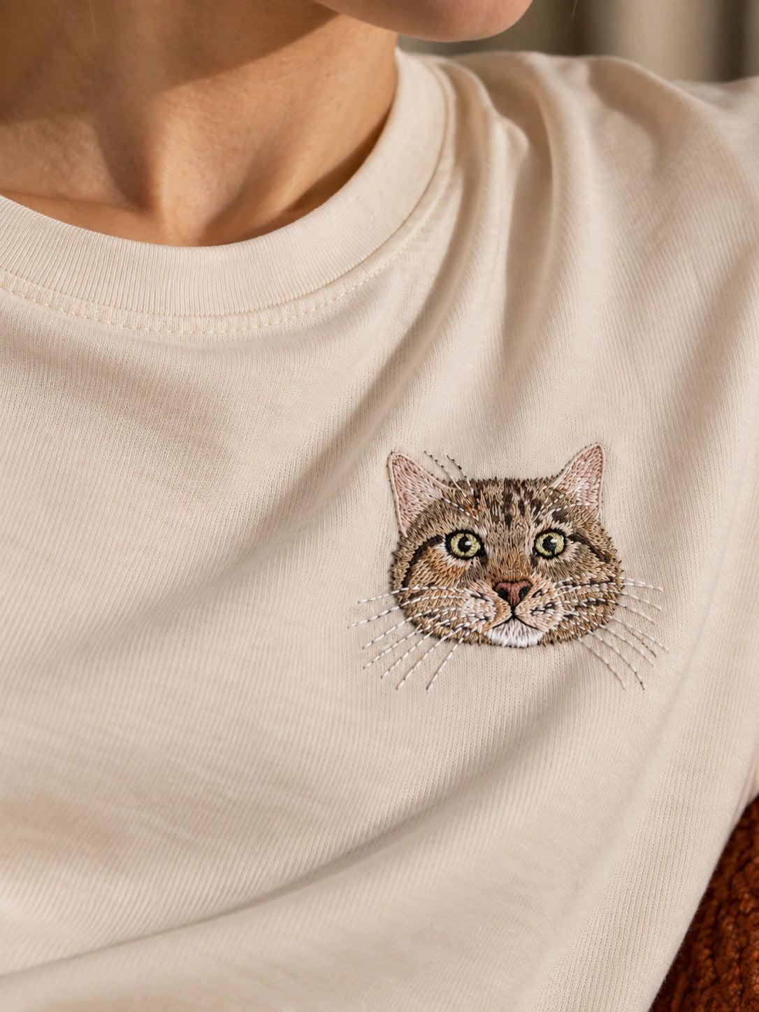 A custom cat portrait embroidered on a cream T-shirt